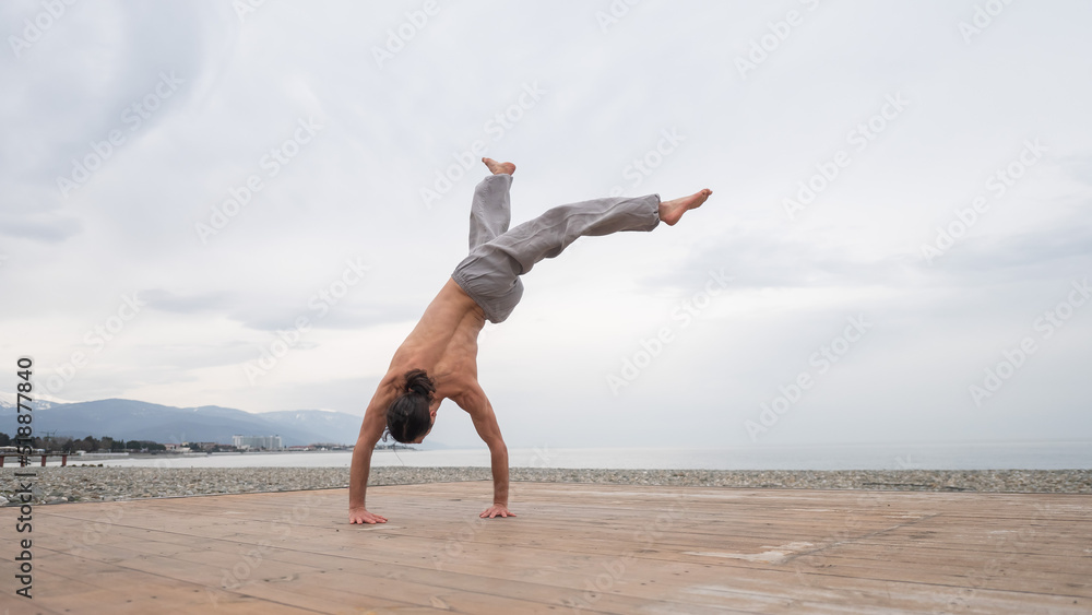 Obraz premium Shirtless caucasian man doing backflip on pebble beach. 