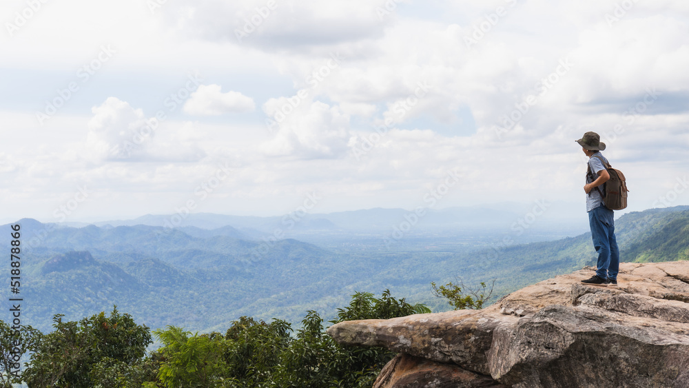 Asian man travel and standing on the edge of the mountain with forest landscape background.Concept of travel in spring season at Thailand.