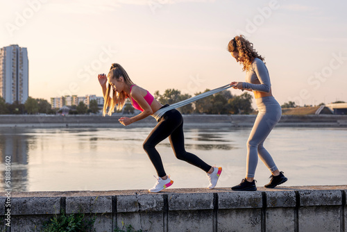 Two woman exercise and stretching outside near the river