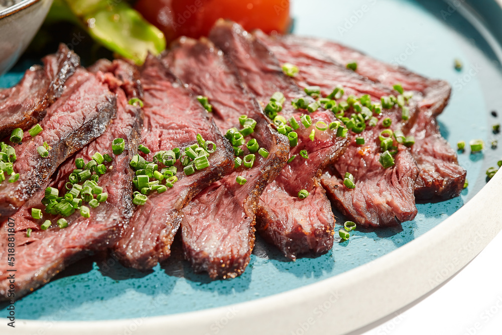 Roast beef with vegetables and sauce on trendy plate. Sliced meat steak roast grill with tomatoes and broccoli isolated on white table. Angus roast beef in healthy style for restaurant.