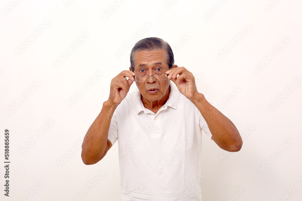 Wow and amazed expression of elderly asian man while standing and holding his glasses.