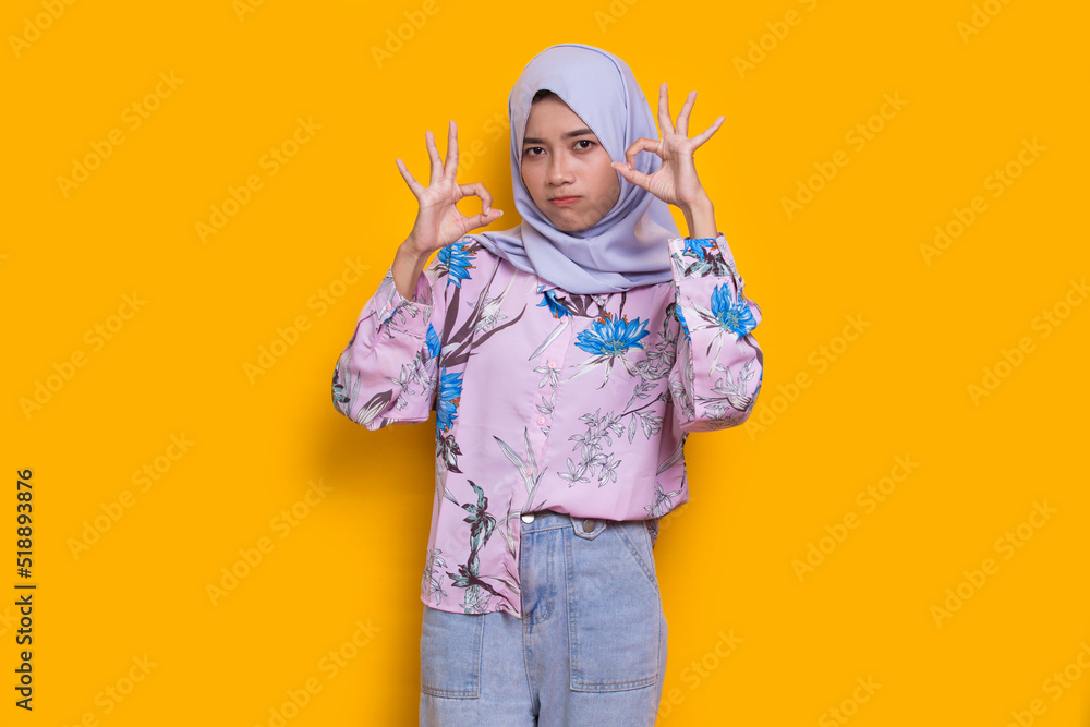 young asian beautiful muslim woman with ok sign gesture tumb up isolated on yellow background
