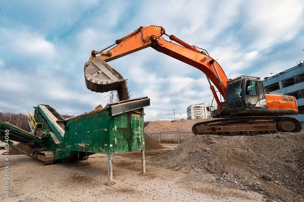 Excavator loads soil in mobile crushing and sorting complex Excavator loads soil in mobile crushing and sorting complex