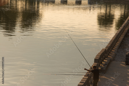 Fisherman with a fishing rod on the river bank