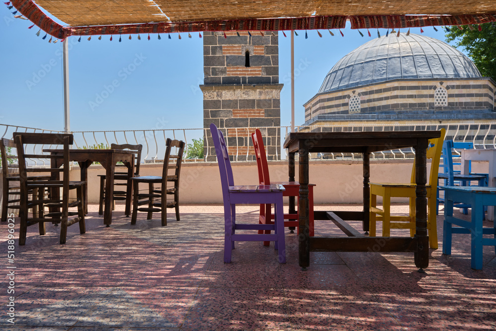 Fototapeta premium empty wooden chairs and tables at the roof Sheikh Matar Mosque and dubbed the Four-legged Minaret in Diyarbakir, Turkiye. Local name is seyh matar cami ve dort ayakli minare.