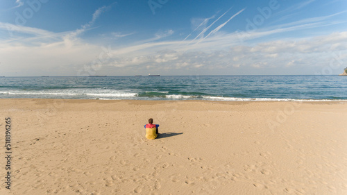 Lonely man sitting on the calm beach, thinking and self observing