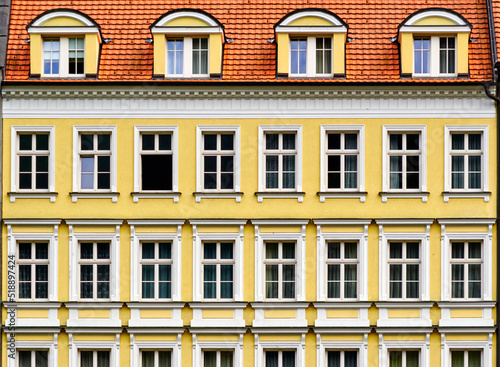 Fototapeta Geometrically strict yellow facade with uniformly arranged windows under a red t