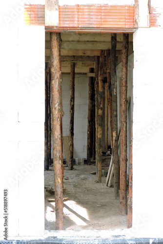 A rough door opening, reinforced brick lintels, walls made of autoclaved aerated concrete and wooden building props inside a house under construction  © E-lona