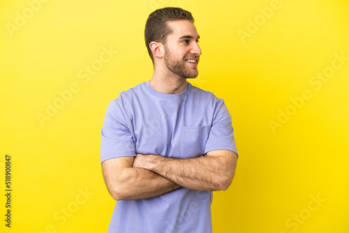 Handsome blonde man over isolated yellow background happy and smiling