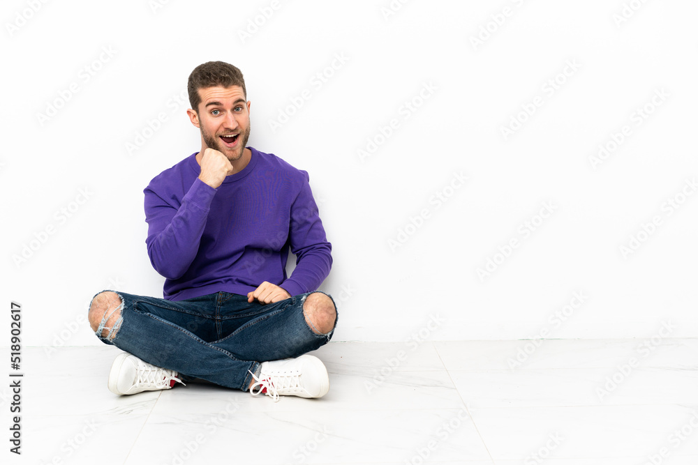 Young man sitting on the floor celebrating a victory Young man sitting on the floor celebrating a victory
