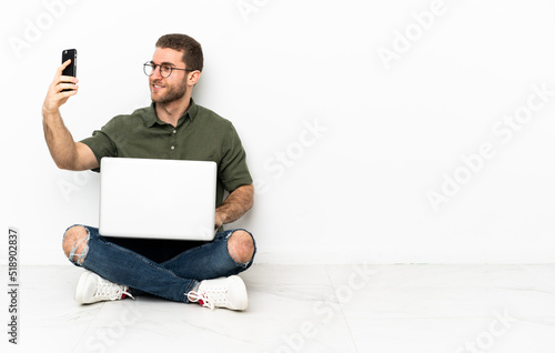 Young man sitting on the floor making a selfie