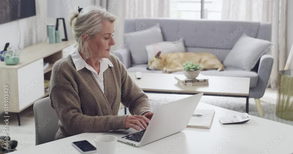Mature author typing on a laptop while looking over at her diary to compare notes and ideas for her story book. Female writer working on her latest novel, bestseller or fictional literature at home Mature author typing on a laptop while looking over at her diary to compare notes and ideas for her story book. Female writer working on her latest novel, bestseller or fictional literature at home