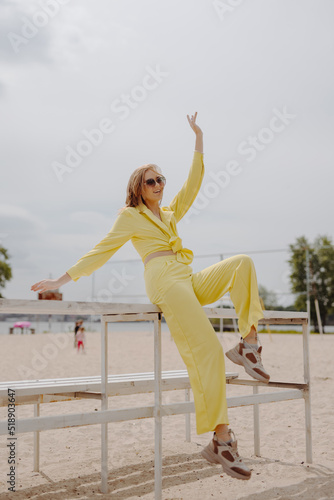Happy young woman in yellow clothes on the beach