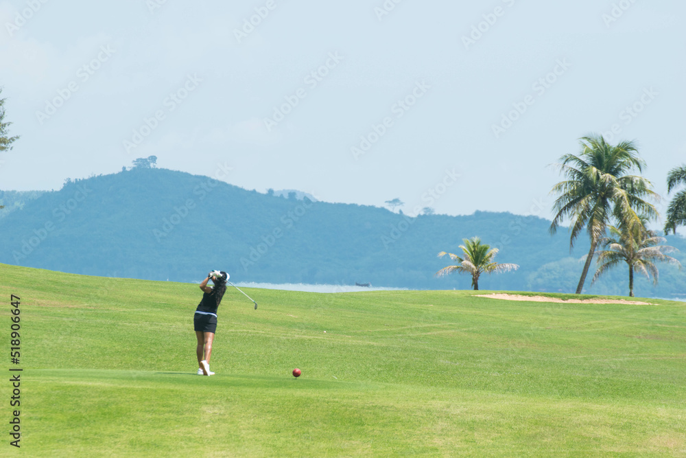 Long shot women from behide hitting golf on golf course