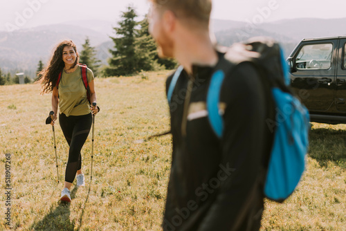 Smiling couple starting walking with backpacks over green hills
