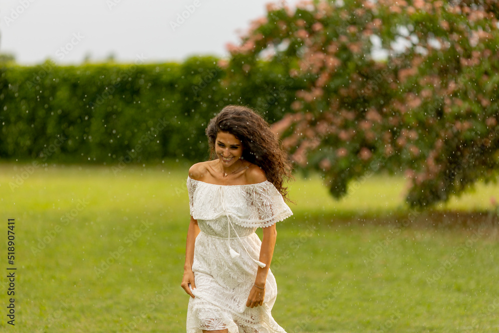 Joyful young woman caught by the summer rain in the park Joyful young woman caught by the summer rain in the park