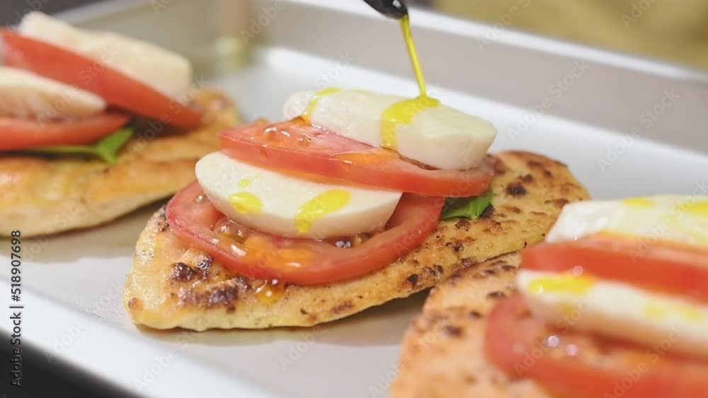 Chef pours olive oil on chicken fillet with tomatoes, mozzarella and basil.
Chef pours olive oil on chicken fillet with tomatoes, mozzarella and basil.