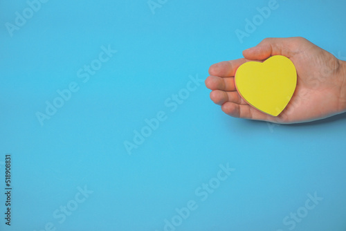 Red ribbon in hand with blue background  heart health  donate  happy volunteer charity  corporate social responsibility  world heart day  world health day  world mental health day   concept