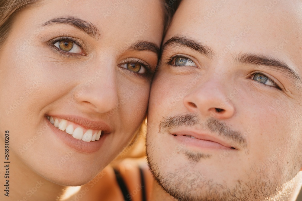 A close photo of faces of the lovers which are cuddling up to each other in the modern urban space at sunset in Spain. A couple of tourists on a date in the evening in Valencia.