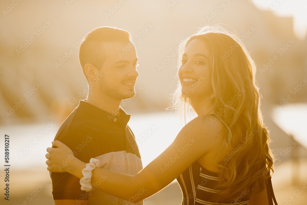 A couple of tourists is dancing in the modern urban space on a date at the sunset in Valencia. A girl is holding hands with her boyfriend in the evening in Spain.