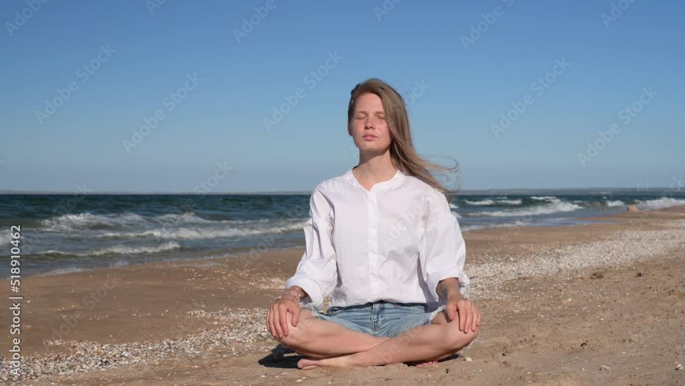 Girl meditating by the sea. Wind shakes long blond hair Girl meditating by the sea. Wind shakes long blond hair