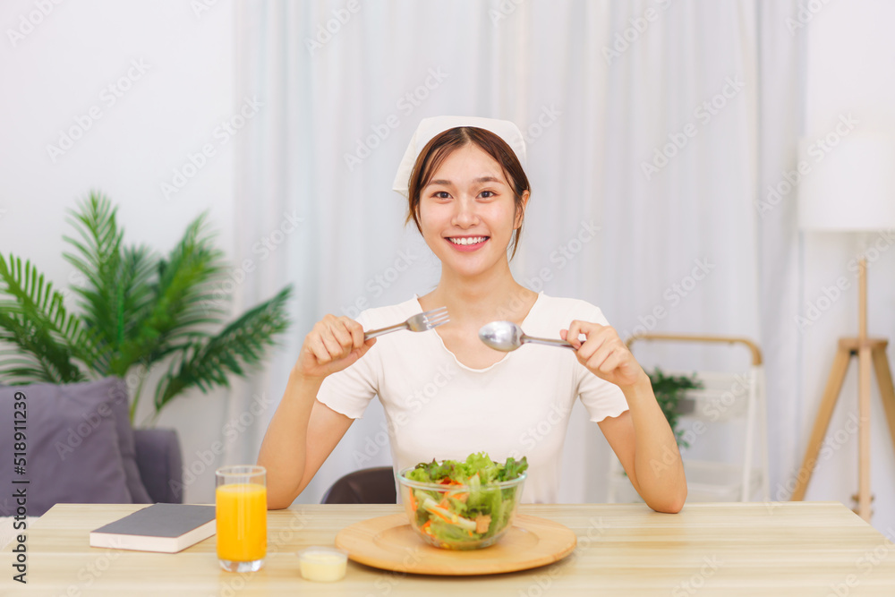 Lifestyle in living room concept, Young Asian woman eating vegetable salad and orange juice Lifestyle in living room concept, Young Asian woman eating vegetable salad and orange juice