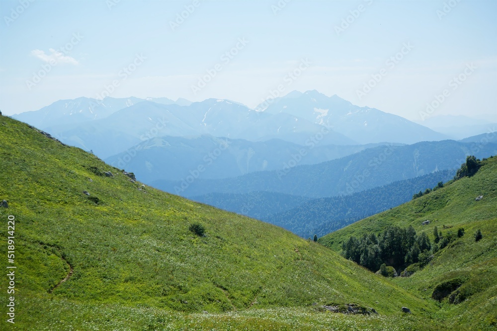 Summer mountain landscape. High mountains and above the mountains a bright blue sky