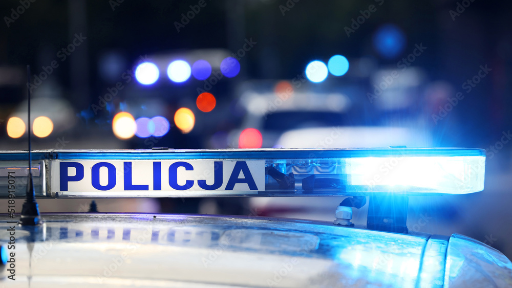 Akcja policji wieczorem w mieście. - Sygnalizator błyskowy niebieski na dachu radiowozu policji polskiej w nocy. - obrazy, fototapety, plakaty 