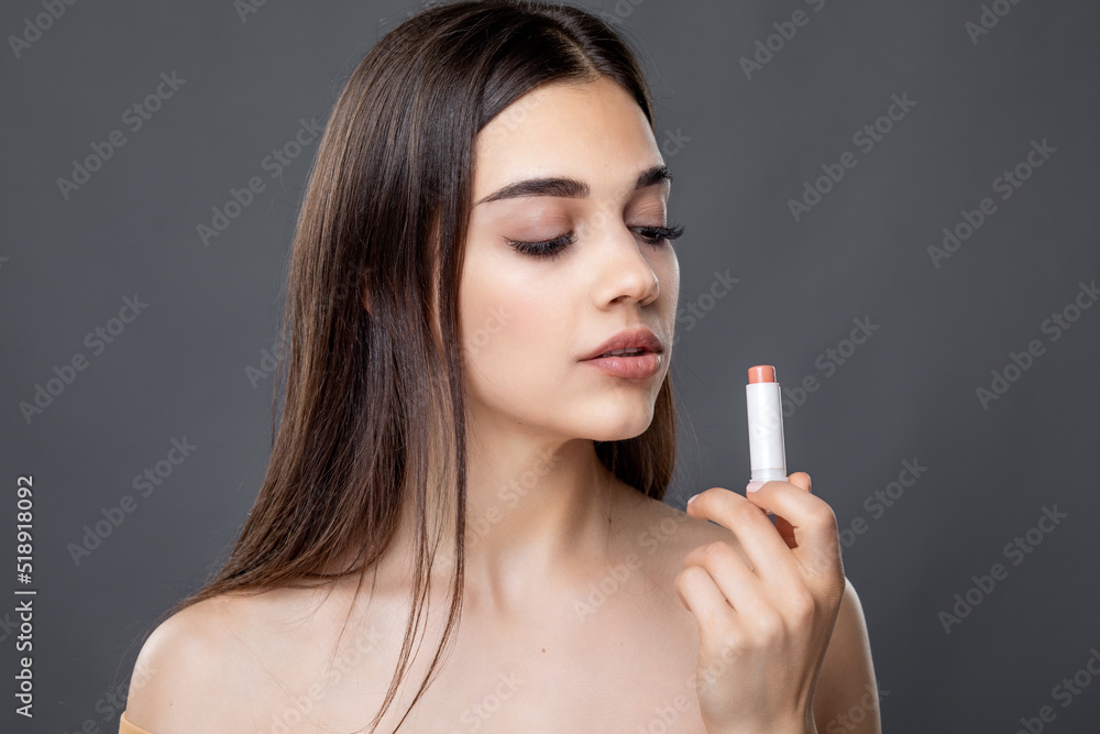 Obraz premium Young beautiful woman tests smell and applying lipstick or lip balm, skin and lips care, Chap protection