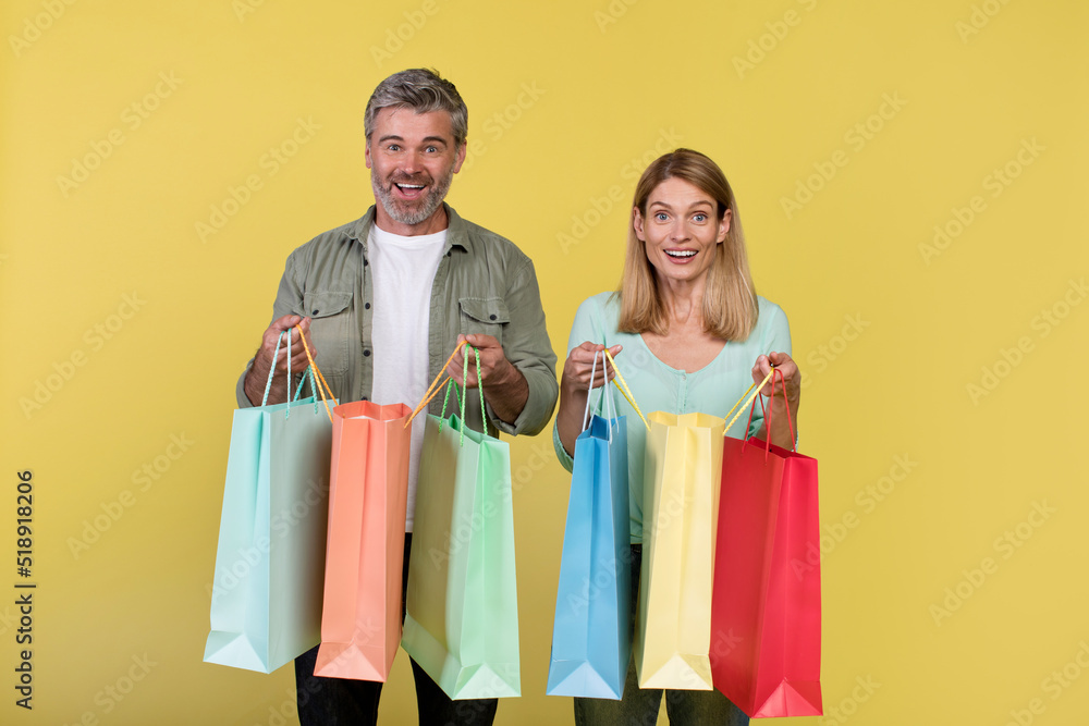 Big sale and shopping with pleasure. Excited middle aged spouses holding many colored packages in hands Big sale and shopping with pleasure. Excited middle aged spouses holding many colored packages in hands