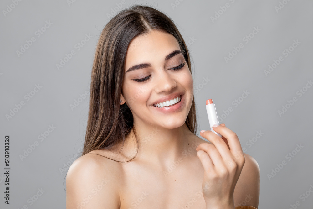 Young beautiful happy smiling woman applying lipstick or lip balm, skin and lips care, Chap protection - obrazy, fototapety, plakaty 