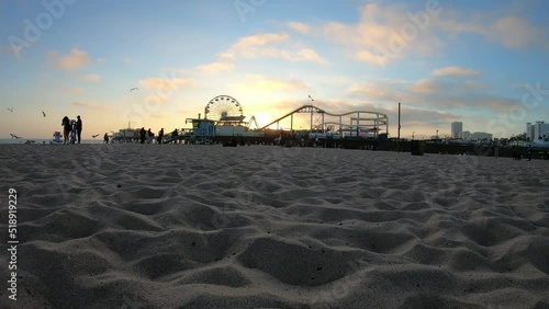 Los Angeles, California, USA, June 21, 2022: TIMELAPSE - View of Santa Monica Beach and the Pier at sunset. Santa Monica Ferris Wheel and Roller-coaster.