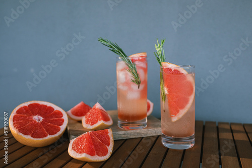 Fototapeta Naklejka Na Ścianę i Meble -  Refreshing summer cocktail with grapefruit, sparkling water, sprig of rosemary and ice cubes. Fresh grapefruit cocktail.