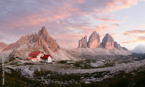 Stunning panoramic view of the Three Peaks of Lavaredo, (Tre cime di Lavaredo) Mount Paterno and a refuge during a beautiful sunset. 