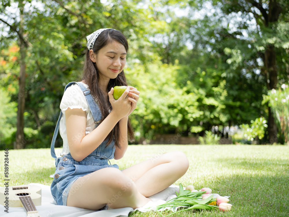 Young girl person holding apple fruit, fresh vitamin diet, healthy lifestyle, portrait. Joyful beautiful Asian teenage happy sitting outdoor leisure activity in green park. Smiling child play apple Young girl person holding apple fruit, fresh vitamin diet, healthy lifestyle, portrait. Joyful beautiful Asian teenage happy sitting outdoor leisure activity in green park. Smiling child play apple