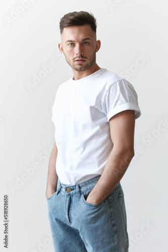 Portrait shot of handsome pensive romantic serious tanned man guy in basic t-shirt looks at camera posing on white background. Fashion Style New Collection Offer. Copy space for ad. Model snap