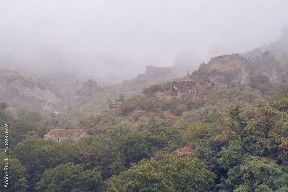 Fototapeta premium Fog view on the Khndzoresk ancient cave city in the mountain rocks. Armenia landscape attraction. Abandoned ruins in the mist. Atmospheric stock photography.