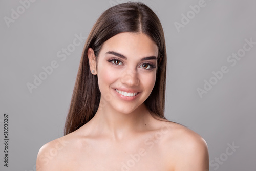 Beautiful young woman with perfect skin. Portrait of beauty model with natural nude make up and touching her face. Spa, skincare and wellness. Close up, copyspace. Stock photo