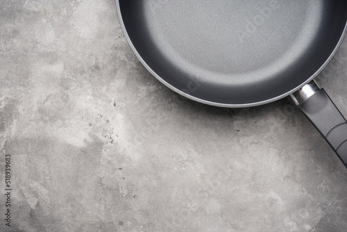 Frying pan and kitchen towel on a gray background, space for text. Top view.