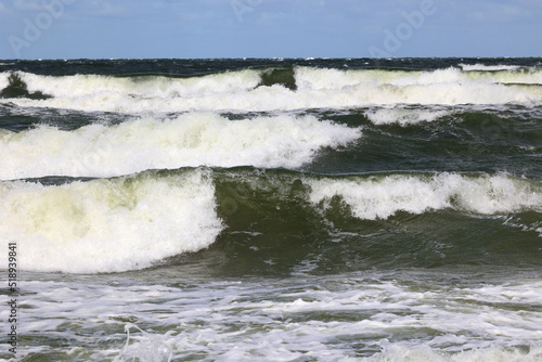 Duża morska fala rozbija się o falochron na wybrzeżu