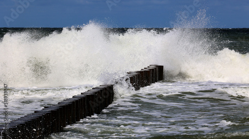 Duża morska fala rozbija się o falochron  na wybrzeżu photo