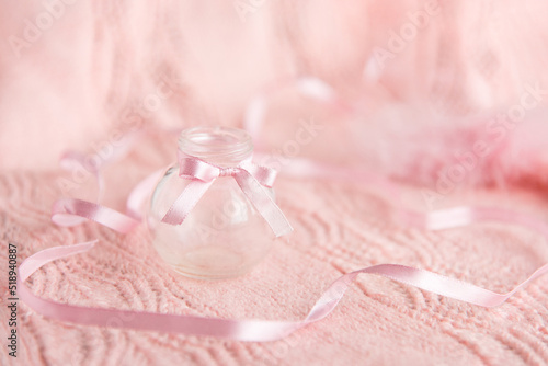 small glass bottle and ribbons on a gentle pink background. Card.