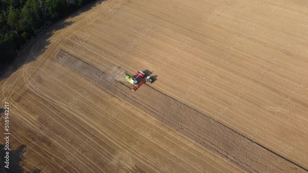 Aerial view of combine harvester and tractor harvesting wheat from field. The camera slowly goes down. Aerial view of combine harvester and tractor harvesting wheat from field. The camera slowly goes down.