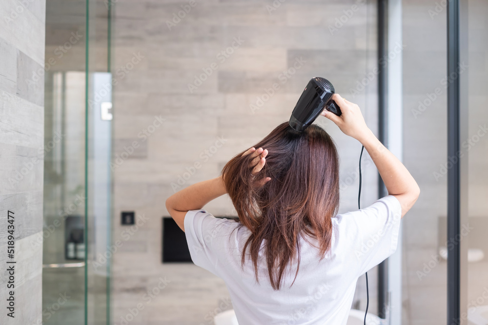Fototapeta premium young woman using hair dryer at home or hotel. Hairstyles and lifestyle concepts