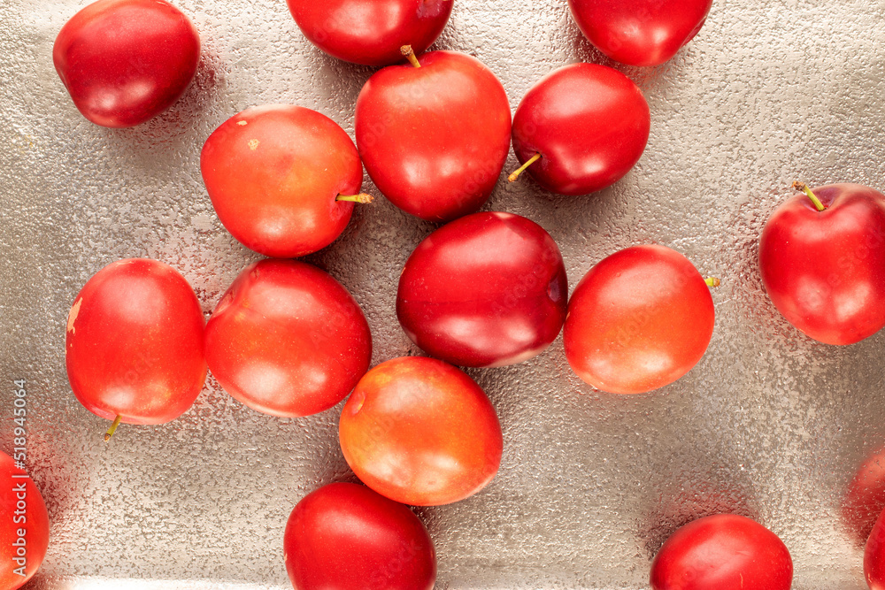 Obraz premium Several organic juicy cherry plums on a metal tray, close-up, top view.