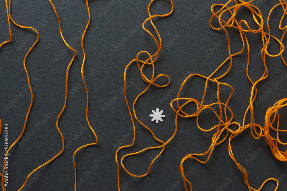 orange string with paper asterisk on dark gray board orange string with paper asterisk on dark gray board