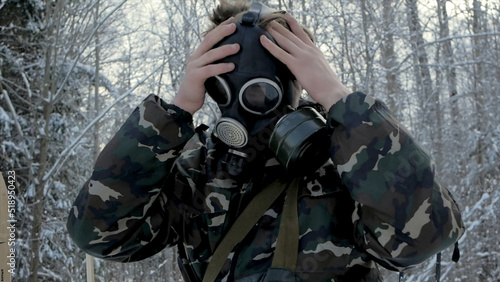 Man in uniform wearing a gas mask in the winter forest. portrait of a young soldier wearing a gas mask against a nature background.