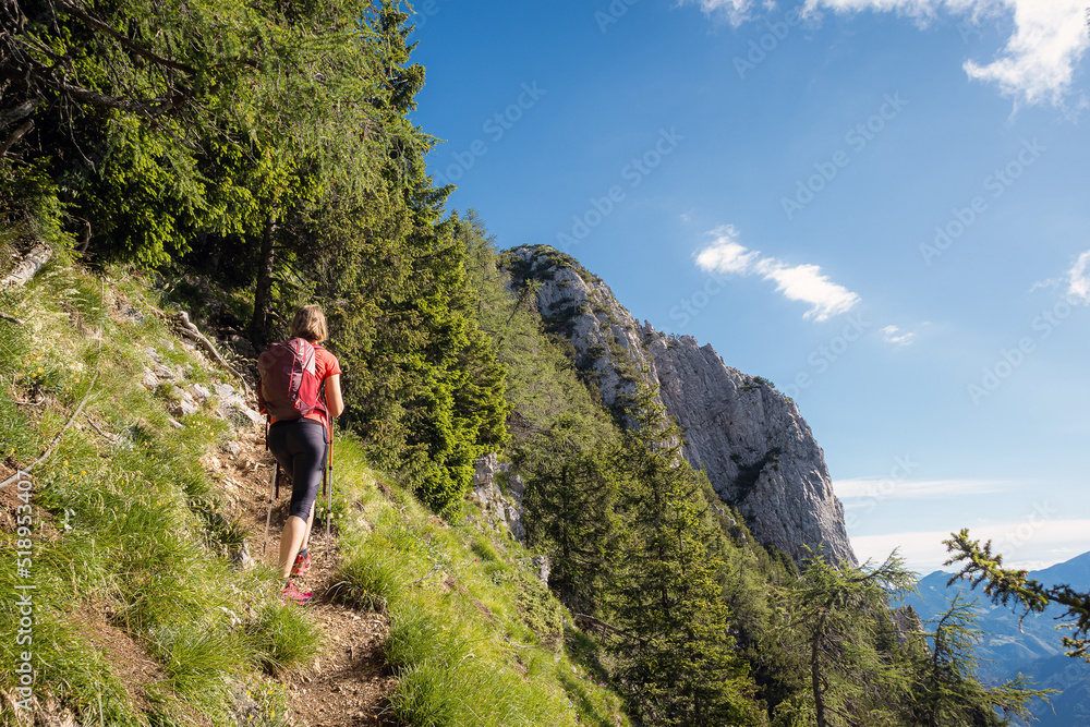Woman backpacker hiking in nature with mountains in background.