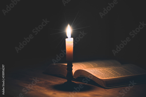 Fotografi Candle with bible on a old oak wooden table.