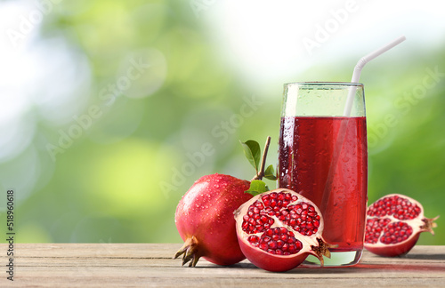 Pomegranate juice with fresh pomegranate fruits on wooden table. photo